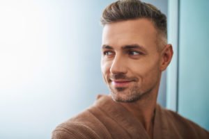 Close up portrait of attractive unshaven gentleman looking away and smiling slightly.